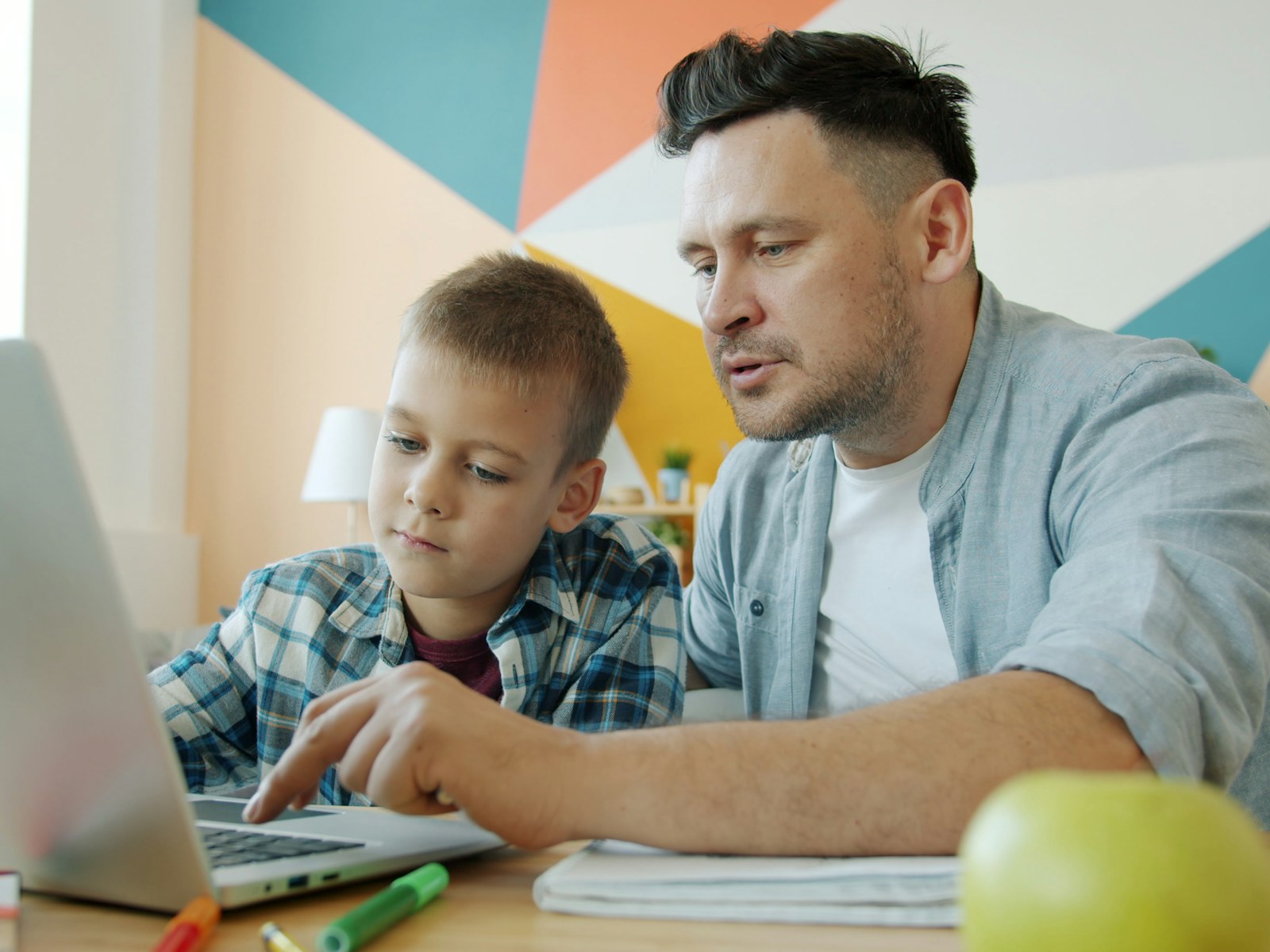 A parent and child using a laptop together at home on Pure Fibre internet